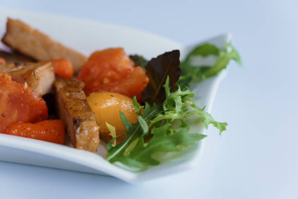 Stewed meat with vegetables and mushrooms on a white plate
