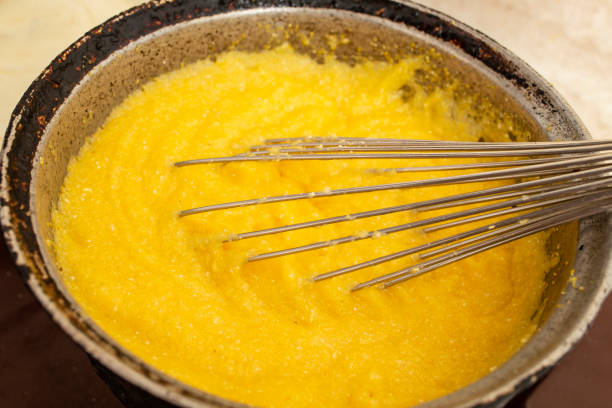 Boiling corn flour in a cast iron pot, making mamaliga, traditional romanian food, and mixing with a stainless steel whisk, soft focus close up Boiling corn flour in a cast iron pot, making mamaliga, traditional romanian food, and mixing with a stainless steel whisk, soft focus mamaliga stock pictures, royalty-free photos & images
