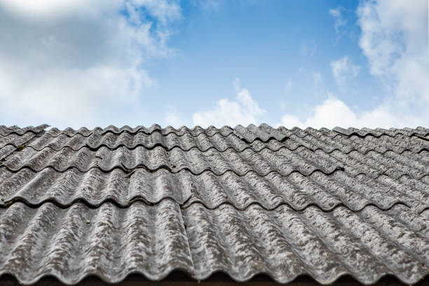 Gray asbestos sheets on a house rooof, pespective view with blue sky