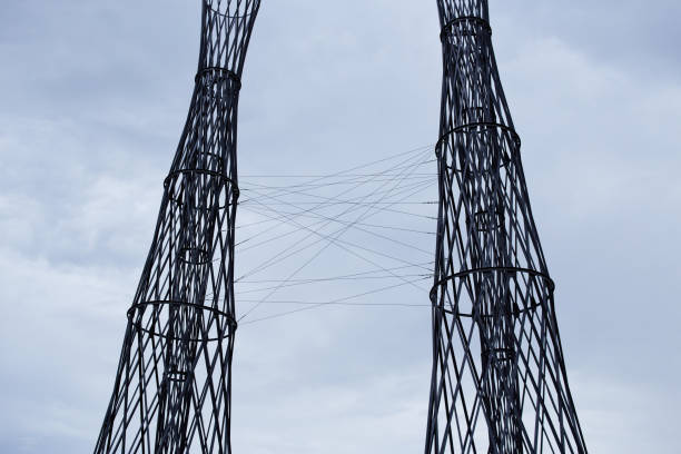 Two metal towers. Steel cables and a structure made of black metal in the angle from below against the background of the blue sky.
