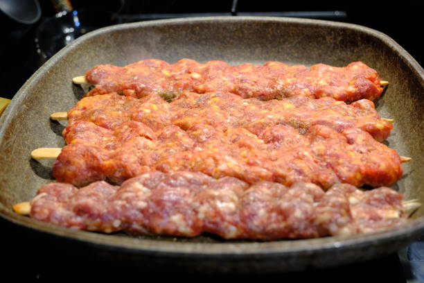 Adana Kebab, the traditional taste of Turkish cuisine. A housewife cooks homemade Adana kebab in a pan. Close-up footage of cooking lavash, kebab in a pan. Traditional Turkish cuisine.