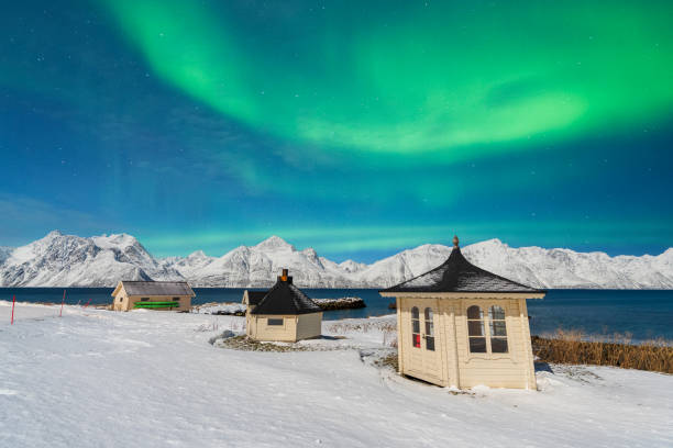 istock Snowy huts and mountains under amazing northern lights (aurora borealis), Norway 2169784352