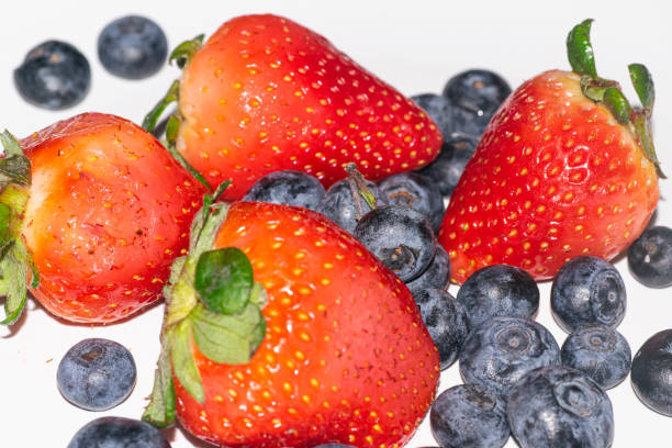 This is a bunch of fresh blueberries and strawberries in a handmade ceramic bowl. The focus is on the front strawberry and falls off towards the back quickly. There is a lot of space for copy above.
