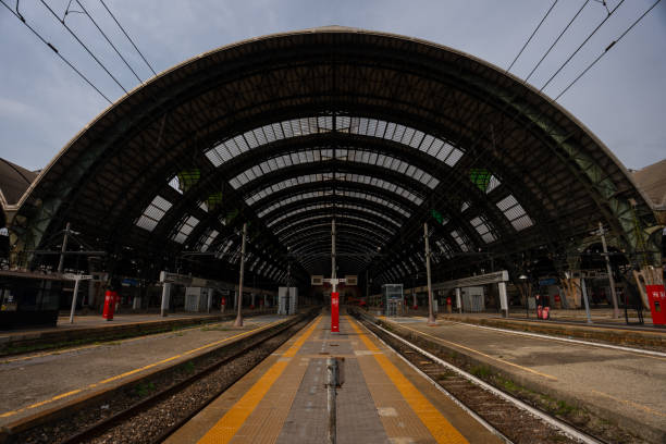 In Bologna, Italy, a view reveals the intricate network of train tracks stretching across the landscape, framed by modern buildings. The skyline reflects the city's urban character on a clear day.