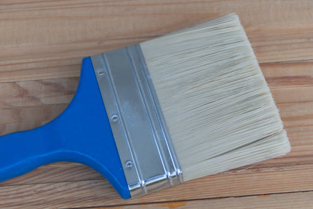 Close-up of an old painted plot with dried blue paint stuck to the end of the plot, abstract background.