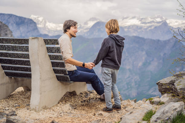 Father and son tourists on background of Breathtaking panoramic view of the Grlo Sokolovo gorge in Montenegro. In the foreground is a mountain, the flat side of which forms a cliff, and the ridge is overgrown with trees. Father and son tourists on background of Breathtaking panoramic view of the Grlo Sokolovo gorge in Montenegro. In the foreground is a mountain, the flat side of which forms a cliff, and the ridge is overgrown with trees. Travel around Montenegro concept. Go Everywhere. green valley denmark stock pictures, royalty-free photos & images