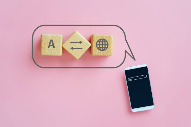 For translator application, foreign languages concept, top view of wooden cube blocks with translation symbol inside speech bubble and smartphone on pink background