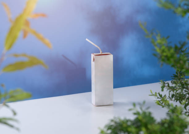 Milk box with drinking straw for mock up with green tree leaves