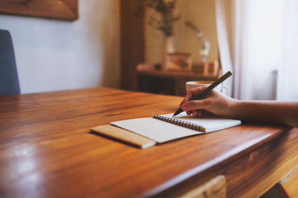 istock Closeup image of a hand writing on a notebook on the table 2169820601