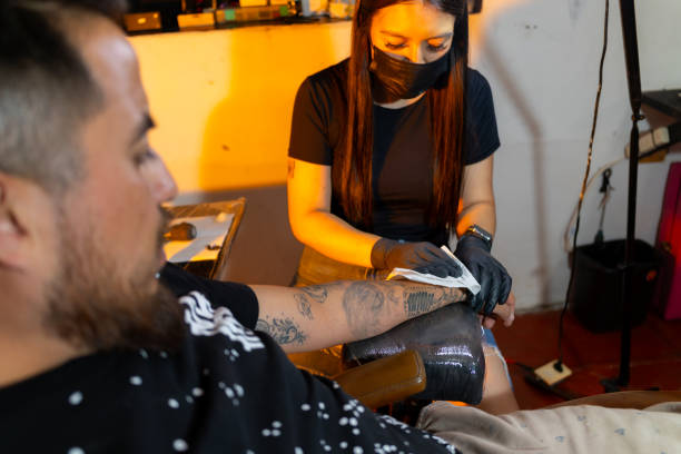 istock Woman tattooing man in her studio 2169821739