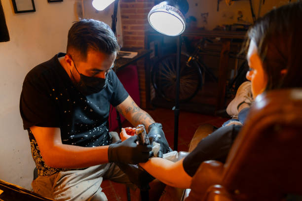 istock Man tattooing woman in his studio 2169821816