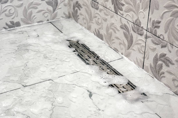 Clogged drain sever system. Close-up of water and foam not flowing out of bathroom shower stall. Maintenance and care of plumbing fixtures in the home.