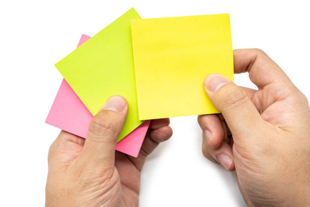 istock Hand holding blank Yellow pink and green sticky note isolated on white background. Copy space. 2169827426