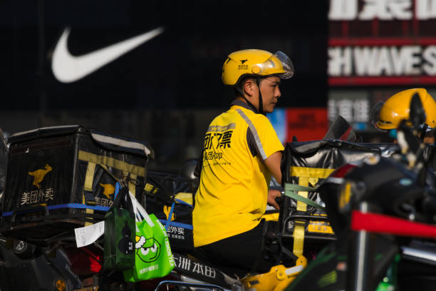 A Meituan delivery driver waits for orders on his motorcycle in front of a Nike store on a hot day on September 1, 2024 in Chongqing, China. The Chongqing Meteorological Observatory continued to issue a red high-temperature warning, marking the 12th consecutive day of such an alert.