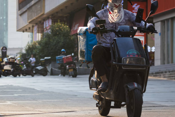 CHONGQING, CHINA - SEPTEMBER 1: A delivery driver wearing a sun-protection face scarf rides an electric scooter on September 1, 2024 in Chongqing, China. The Chongqing Meteorological Observatory continued to issue a red high-temperature warning, marking the 12th consecutive day of such an alert. (Photo by Cheng Xin/Getty Images)