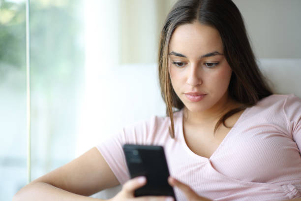 istock Serious woman using smartphone at home 2169839156