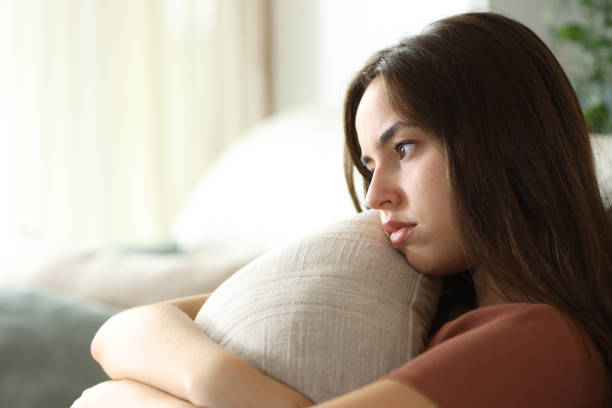 istock Sad woman hugging pillow looking away on a sofa 2169839309