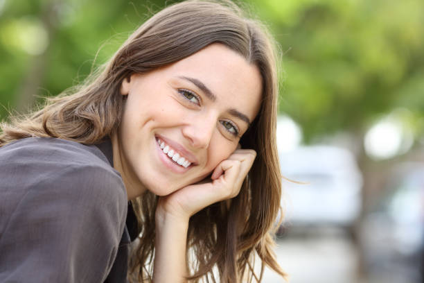 Happy woman with perfect smile and teeth looks at camera in a park stock photo