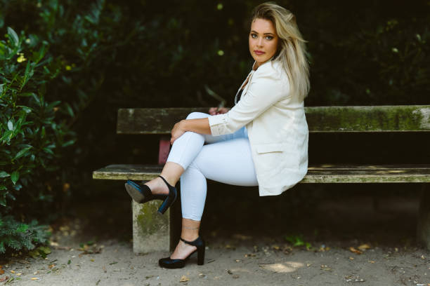 istock woman is sitting on a bench wearing a white jacket and white pants 2169842667