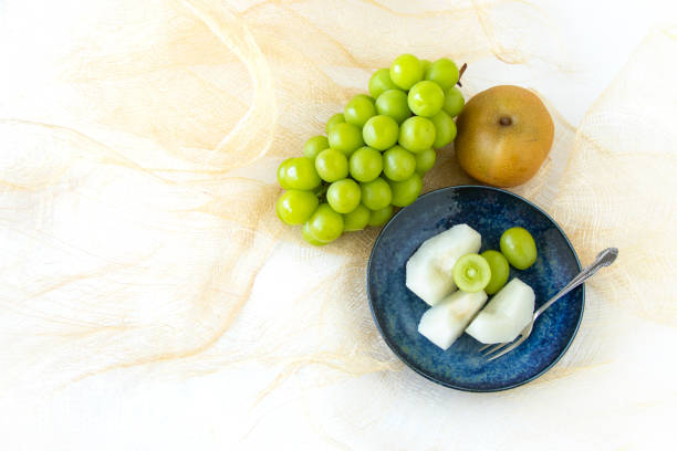 High angle view of red grapes, yellow carrots and pine nuts on cutting board, fresh ingredients to prepare a salad - preparing food and healthy lifestyle, copy space for text