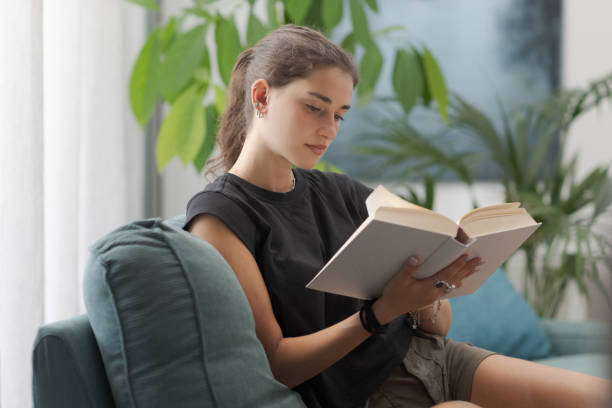 istock Relaxed adolescent girl reading a book at home 2169849507