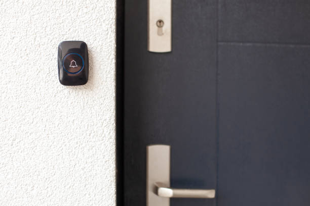 istock Black Doorbell on White Wall by Dark Door 2169849633