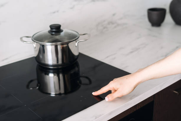 istock Woman press start button on induction cooker, cooking food on kitchen 2169849831