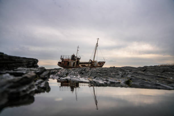 Abandoned rusty fishing boat on rocky shore