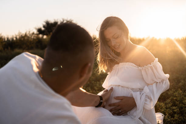 istock Husband touching wife's belly in nature during sunset 2169850888