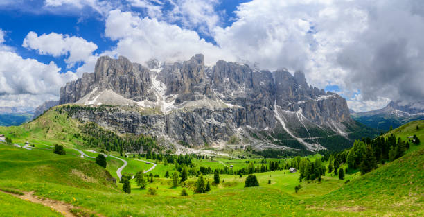Sella group plateau-shaped massif in the Dolomites mountains  seen from the Val Gardena during a sprintime day in the Italian Alps. A footpath is winding through the Alpine meadow alms.