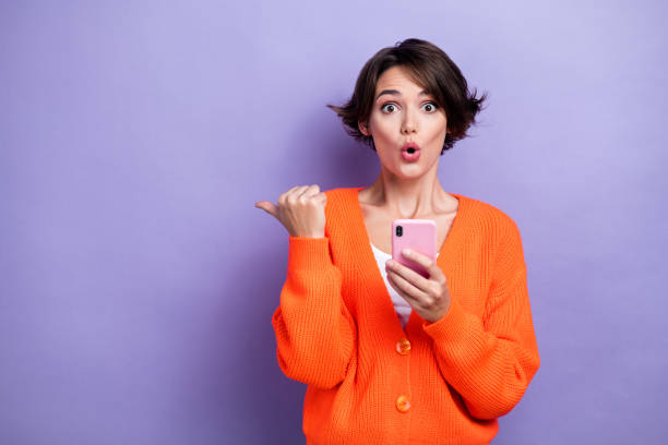 istock Photo of impressed funky lady dressed orange cardigan getting sms modern device thumb empty space isolated purple color background 2169858206