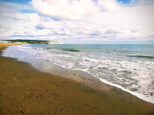 Sandy beach with waves and white cliffs in the distance