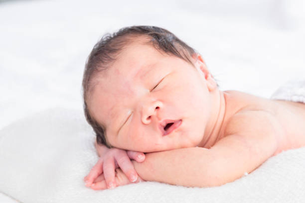 istock Selective focus of Asian little baby peacefully deeply sleeping on white bed with safe, Adorable infant sleep on blanket in bedroom and nature sunlight.Tiny toddler boy soft skin healthy sleep dream. 2169862778