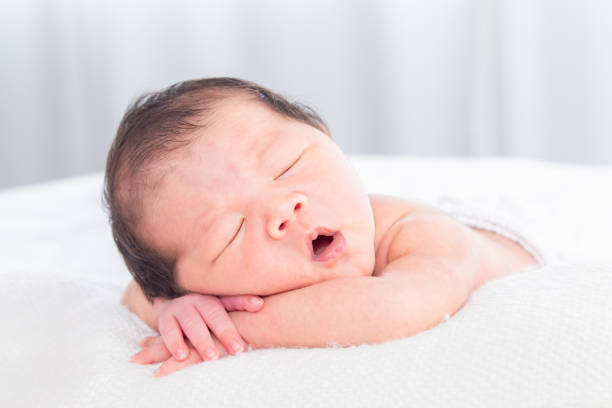 istock Selective focus of Asian little baby peacefully deeply sleeping on white bed with safe, Adorable infant sleep on blanket in bedroom and nature sunlight.Tiny toddler boy soft skin healthy sleep dream. 2169862780