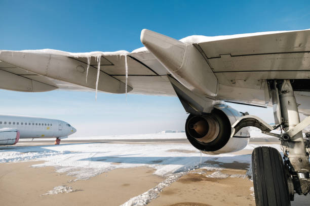 Icicles on aircraft wing on frosty winter day. Airplane at snowy airport.
