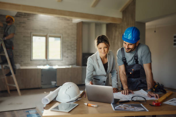 istock Female inspector and manual worker using laptop at renovating house. 2169864269