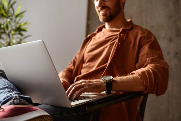istock Partial view of blurred man in shirt using laptop in studio 2169864421