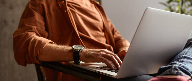 istock Faceless shot of freelancer in shirt using laptop in blurred studio, web banner 2169864434