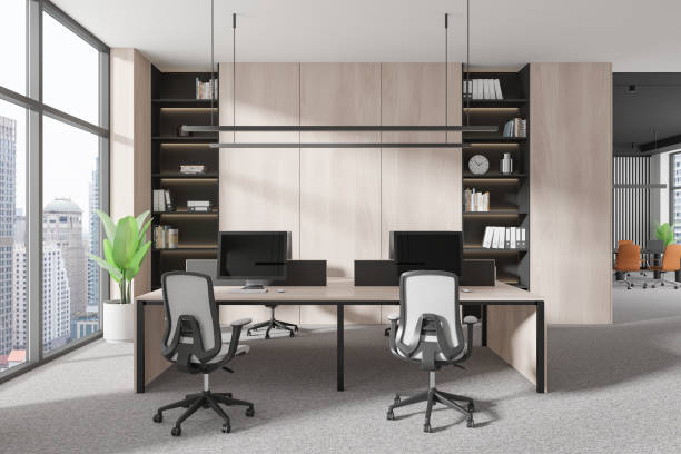 istock Workplace interior with armchairs and desks, pc monitors and shelf near window 2169867232