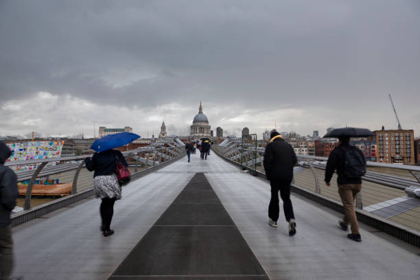 London, England - April 18, 2014: Three young Asian tourists pose for a photo on the Millennium Bridge in front of St Paul's Cathedral in London