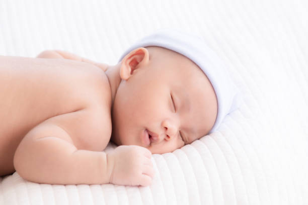 istock Adorable Asian newborn baby deeply sleeping smile Easter costume hat, tiny infant boy soft skin healthy sleep dream on white blanket on bed beautiful sun light, newborn baby health care concept 2169871922