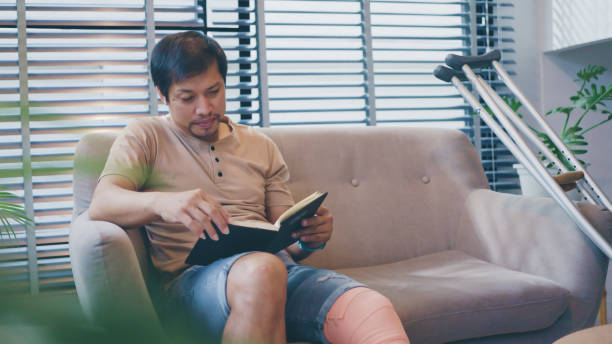 istock A convalescing man sits reading a book at home. 2169871998