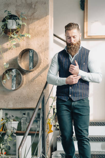 istock Bearded businessman adjusting shirt walking down stairs in office 2169876337