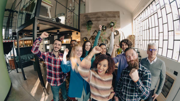 istock Startup team celebrating success raising arms in modern office 2169877193