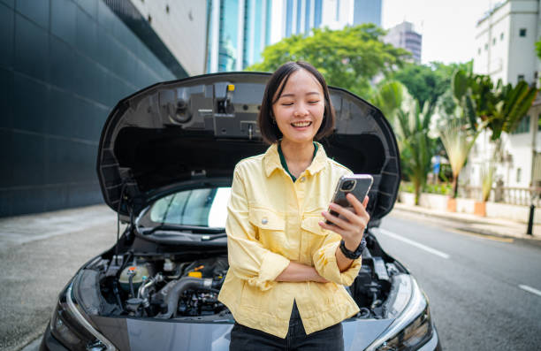 istock Help on the Way: Smiling Asian Woman Waits by Broken Down Car 2169878611