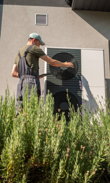 istock Technician working on a heat pump, surrounded by lavender plants in a sunny backyard. 2169882463
