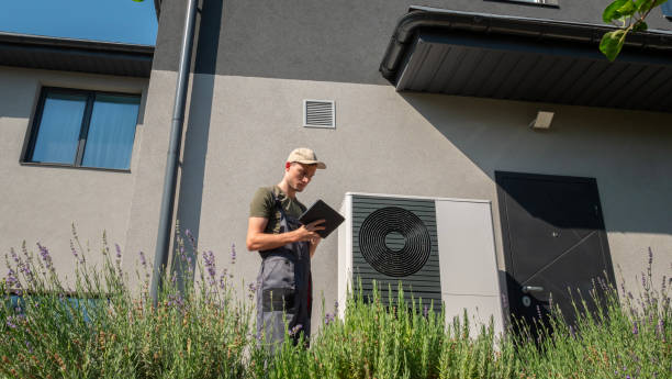 istock A technician adjusting a heat pump unit using a tablet in the garden of a modern home, surrounded by lush greenery on a sunny day. 2169883069