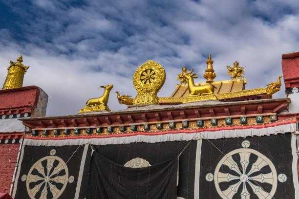 A Tibetan temple dragon and Chinese flag set against the Himalayan mountains surrounding Lhasa at The Jokhang temple.  Architectural features on this Buddhist temple in Barkhor Square in Lhasa, the capital city of Tibet. Tibetans, in general, consider this temple as the most sacred and important temple in Tibet.