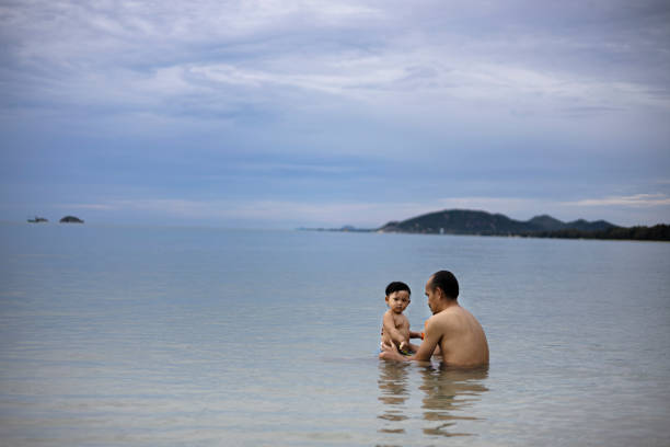 Father and son having fun swimming in the sea. Father teaching his son to swimming.