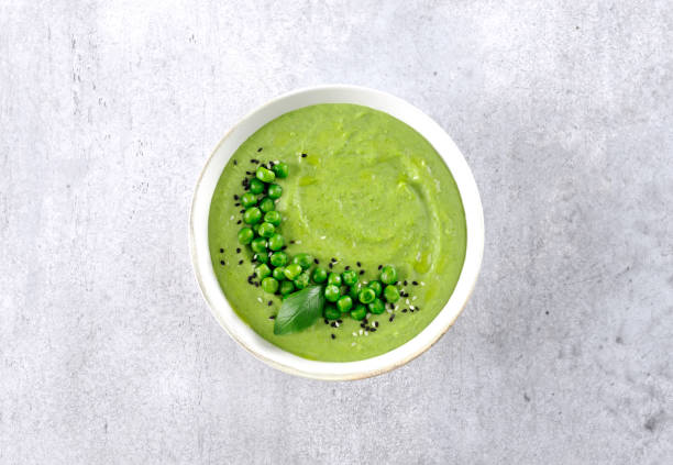 istock Green pea cream soup with crackers on a gray table. Top view. 2169885881